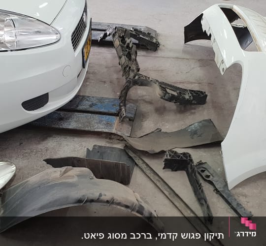 חלקי רכב מפורקים ליד רכב לבן במוסך